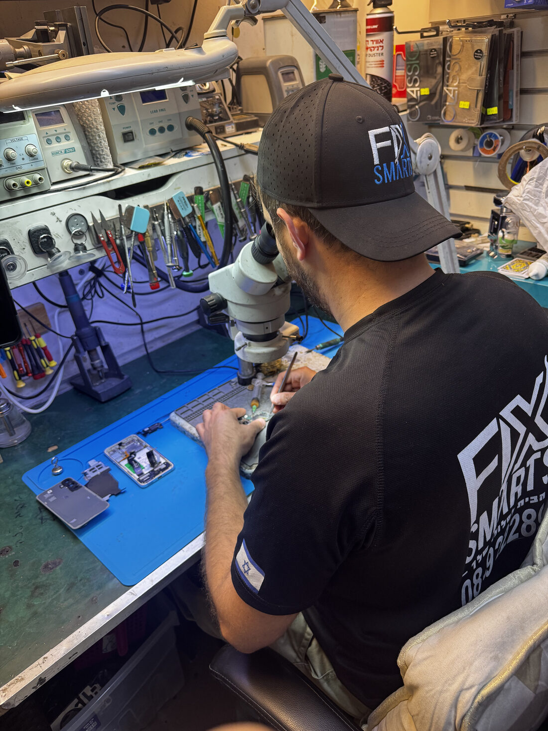 A FixSmarts technician repairing a phone under a microscope in the lab